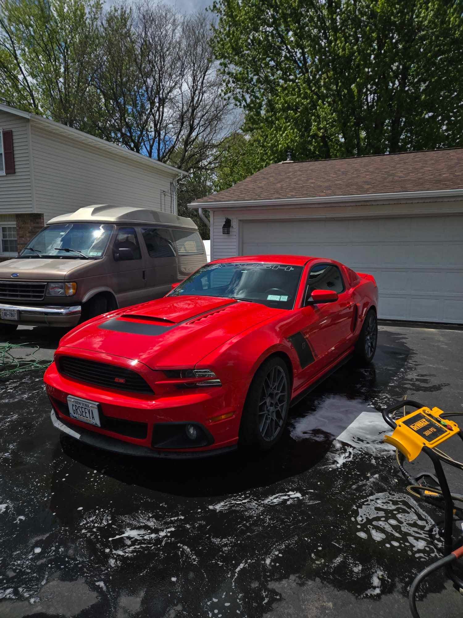 Freshly detailed red Ford Mustang Roush in a customer's driveway